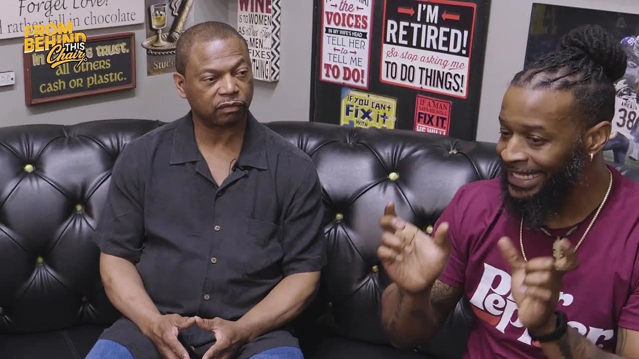 Two men debating, smiling, on the barbershop couch