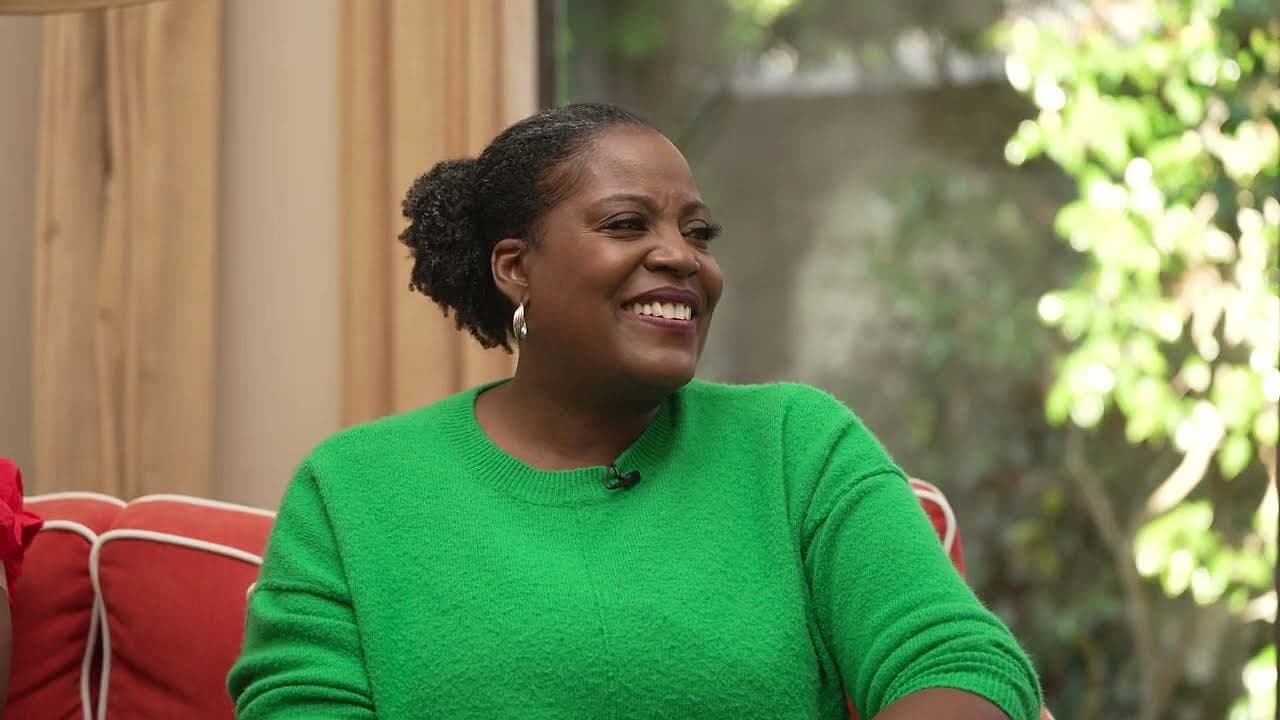 A Watsons host beaming in a green sweater