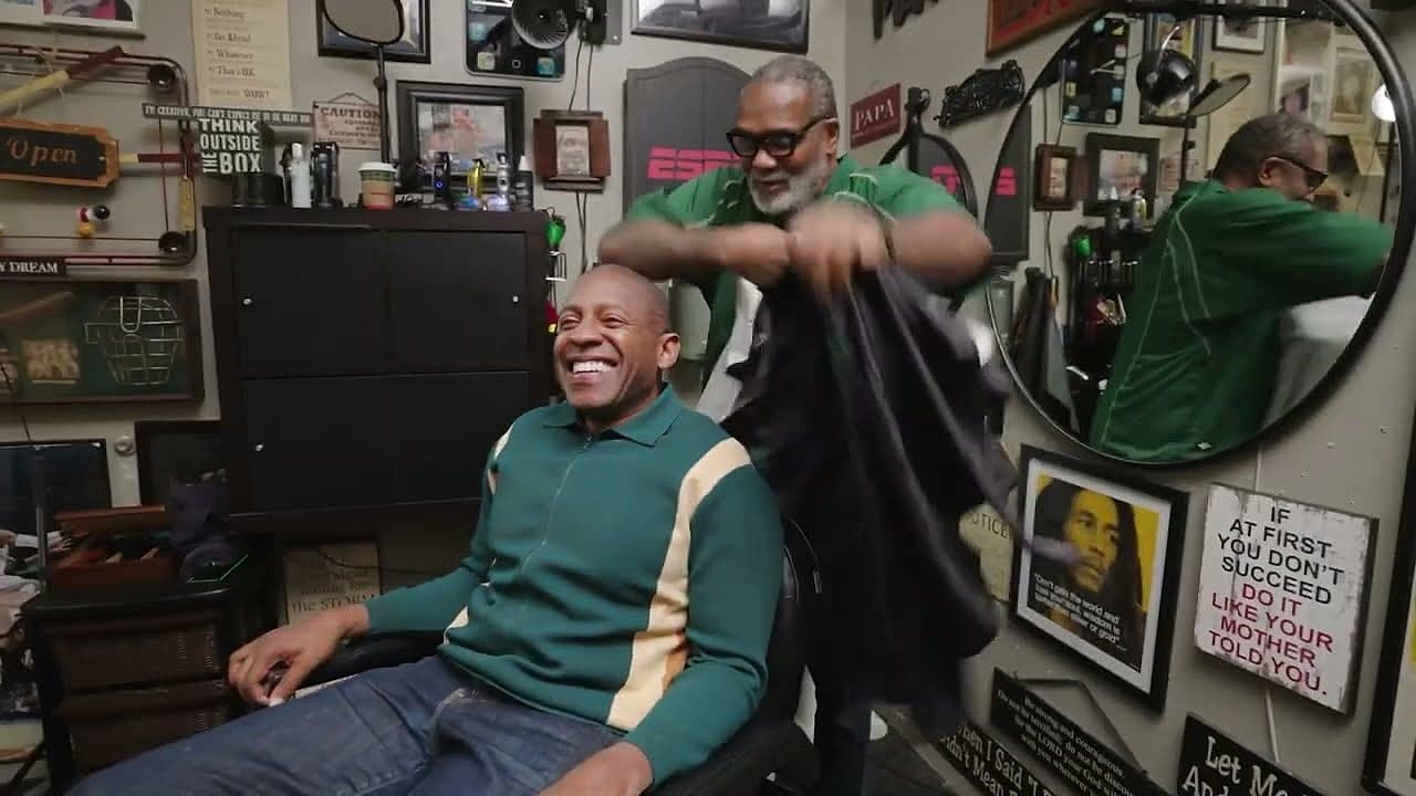 A guest laughing in the barber's chair mid-cut